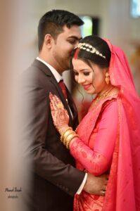 Groom is kissing on the head of the bride and she is looking down while smiling