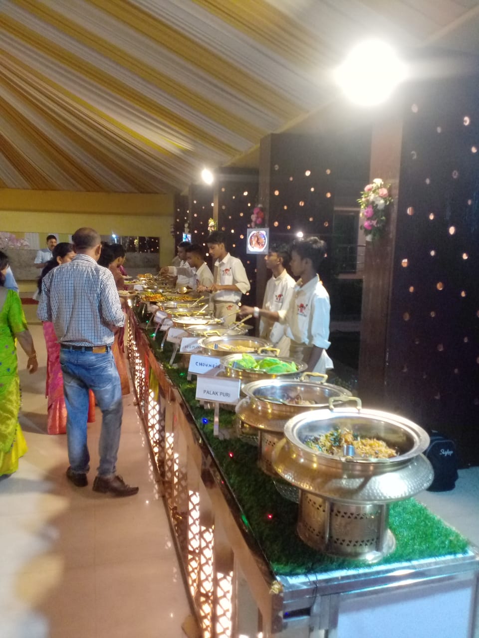 Catering table with various food dishes and peoples are standing near the table