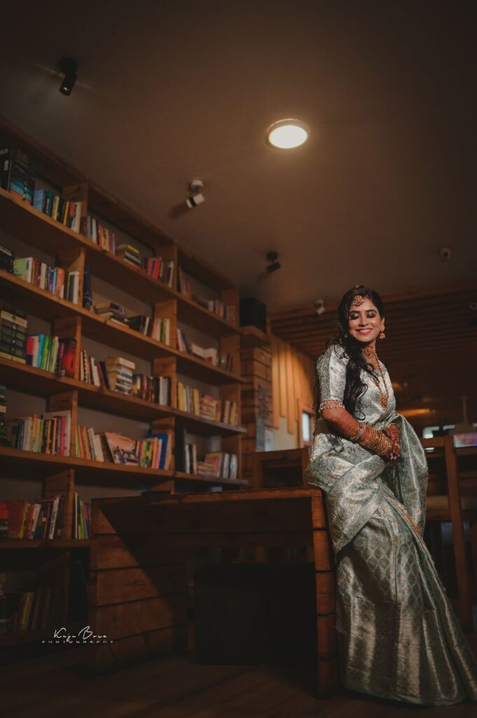 A smiling girl standing in the library surrounded by books.