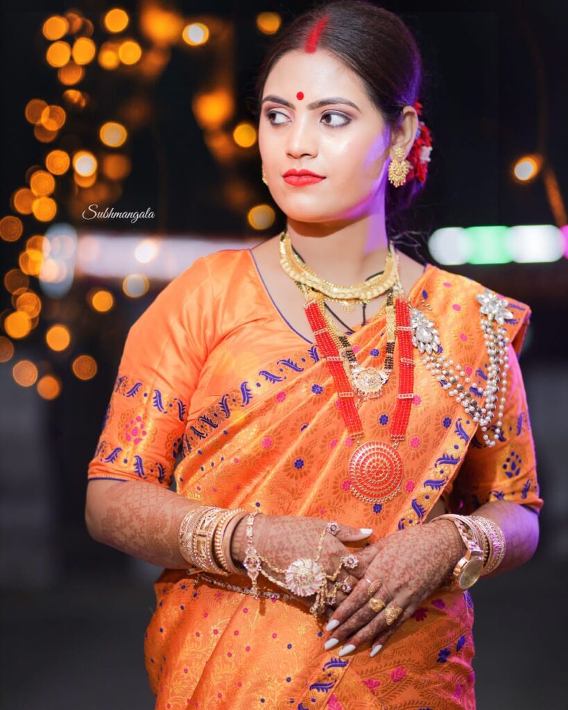 Assamese girl wearing orange mekhela chador.