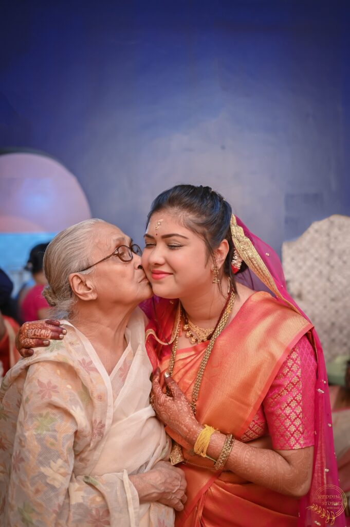 A woman giving a kiss on the bride's face.