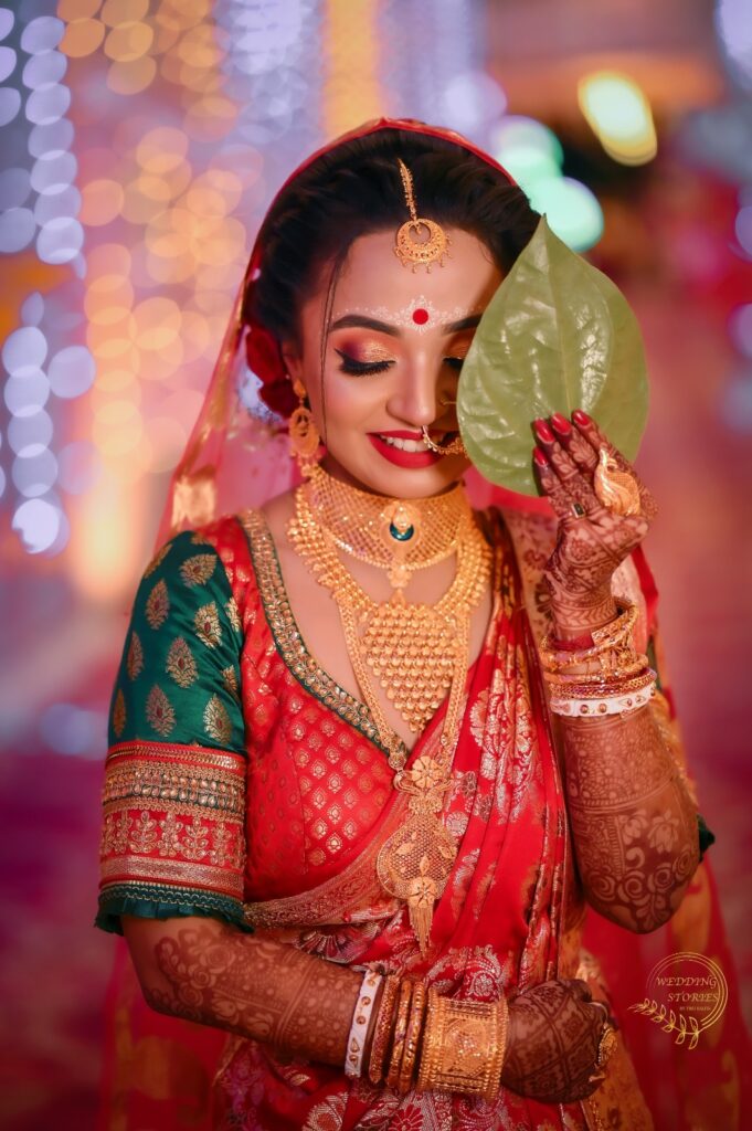 Assamese bride holding a leaf in her hand, smiling.