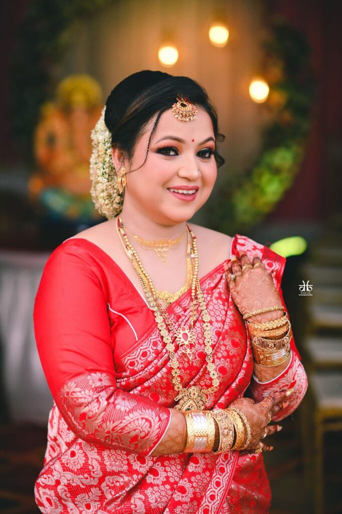 A smiling girl wearing a red mekhela chador.