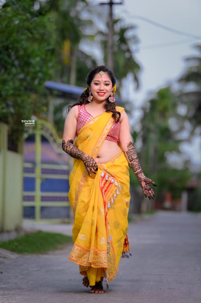 A girl wearing a traditional saree and adorned with henna on her hands.