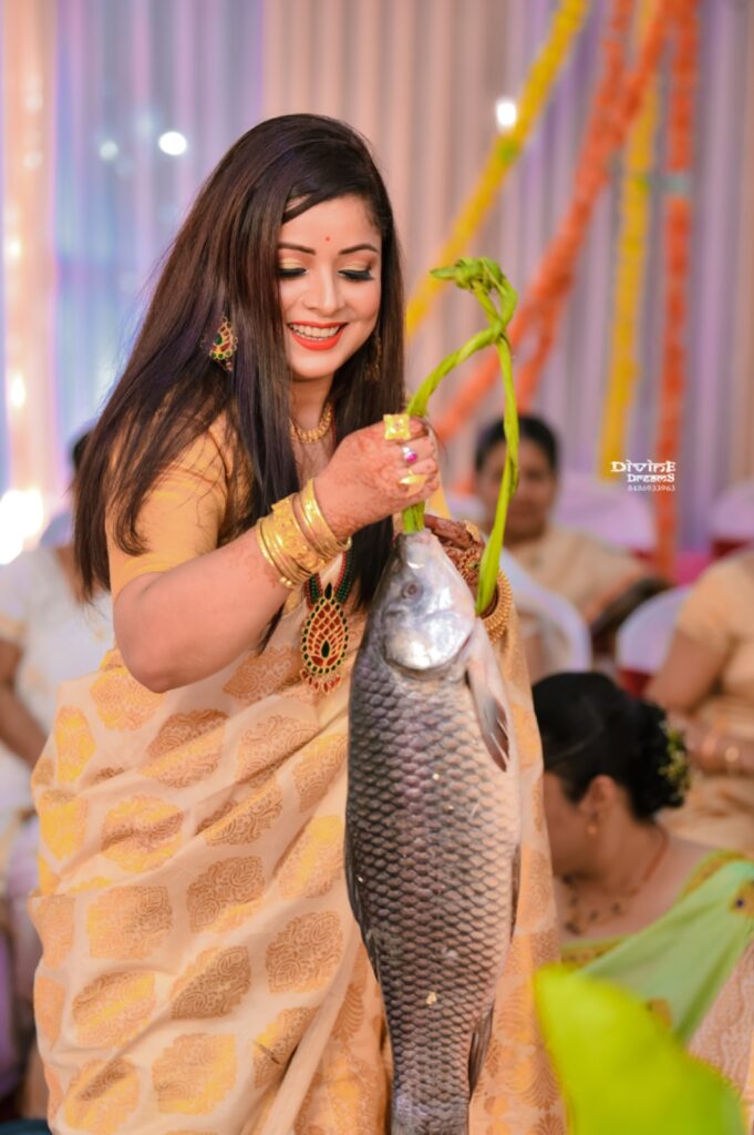 A smiling girl holding fish in her hand.