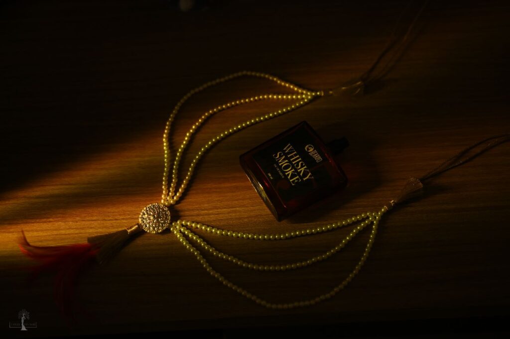A necklace accompanied by whiskey bottle.