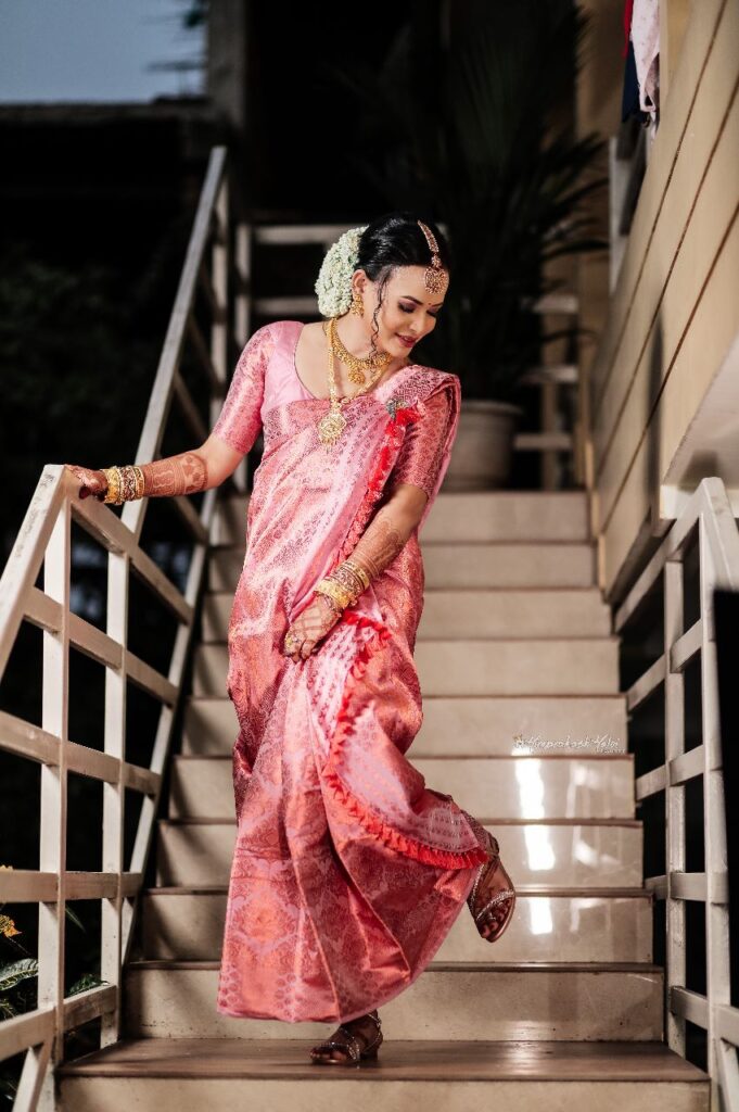 A bride wearing a pink saree and jewelry.