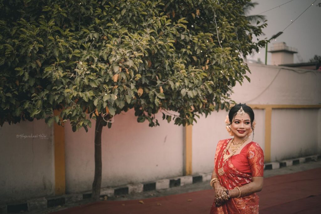 Bride wearing a mekhela chador with a backdrop of tree.