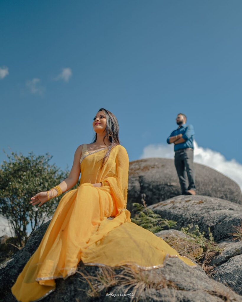 Beautiful girl wearing a yellow sari while a guy stands behind.