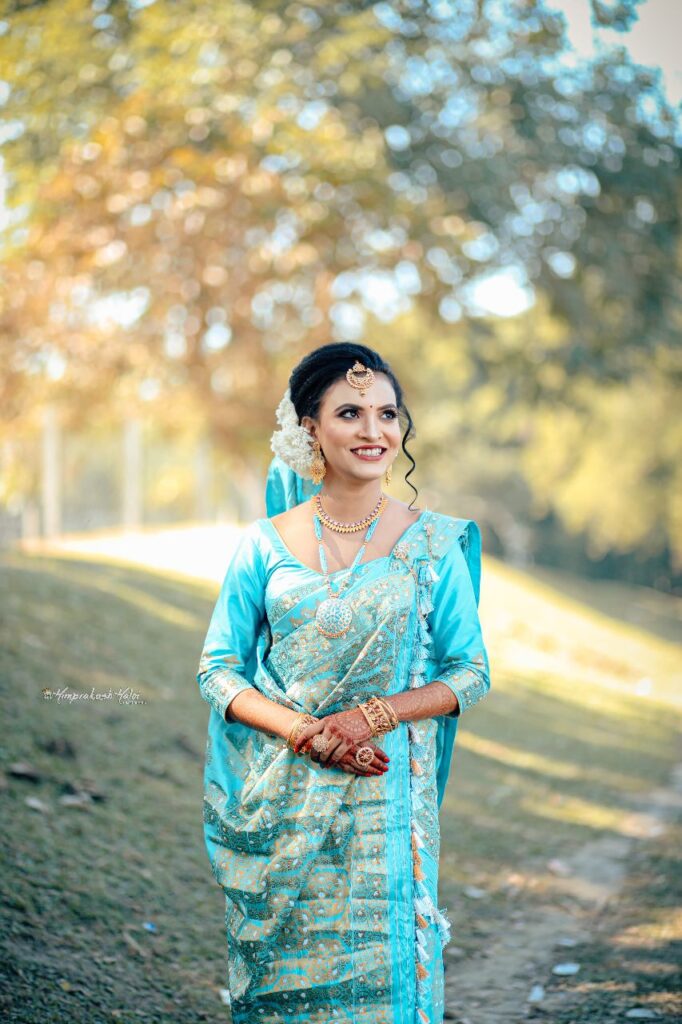 Bride wearing a blue mekhela chador with a joyful smile.