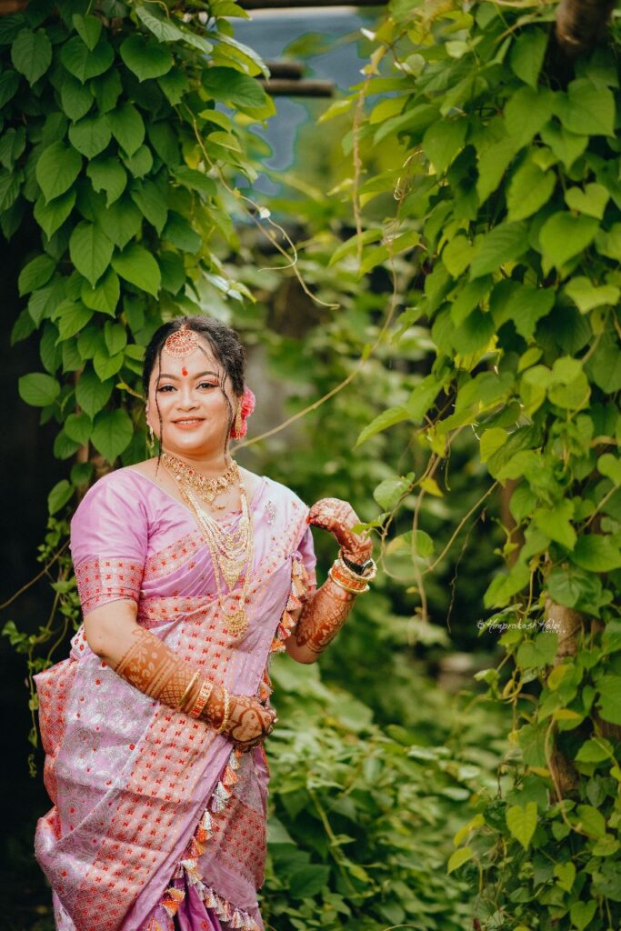 Bride smiling happily against a backdrop of green leaves.