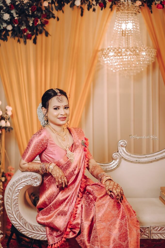 A bride adorned with jewelry and wearing a saree.