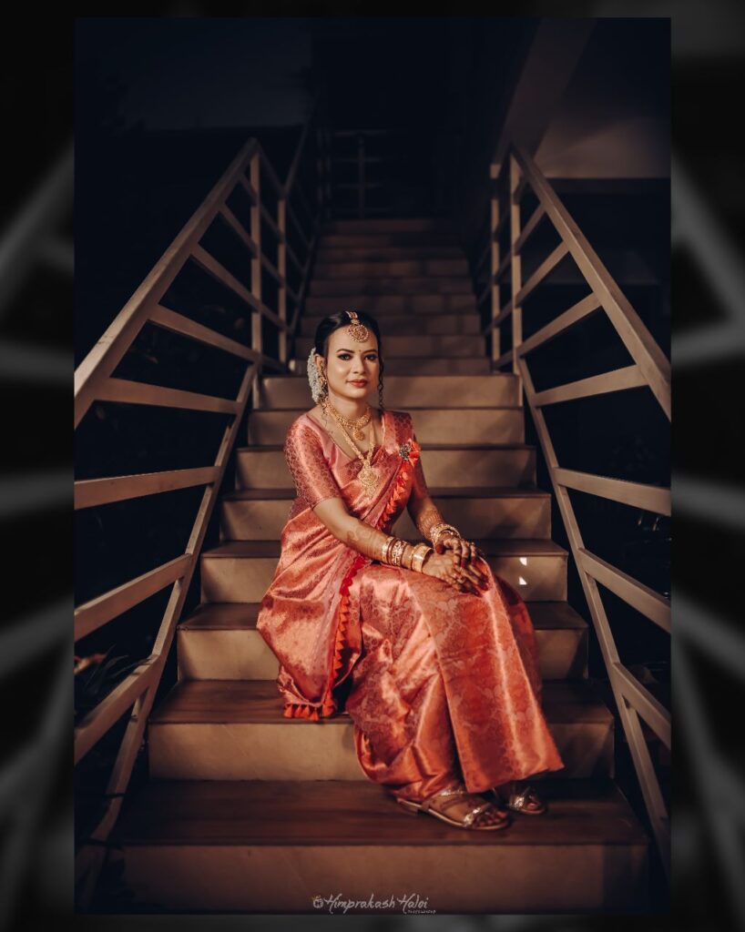 A bride striking a pose for a photo.Bride seated on the stairs wearing a mekhela chador.