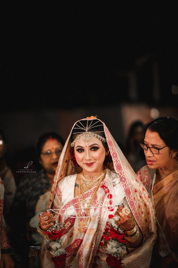 A smiling bride wearing a traditional style mekhela chador.