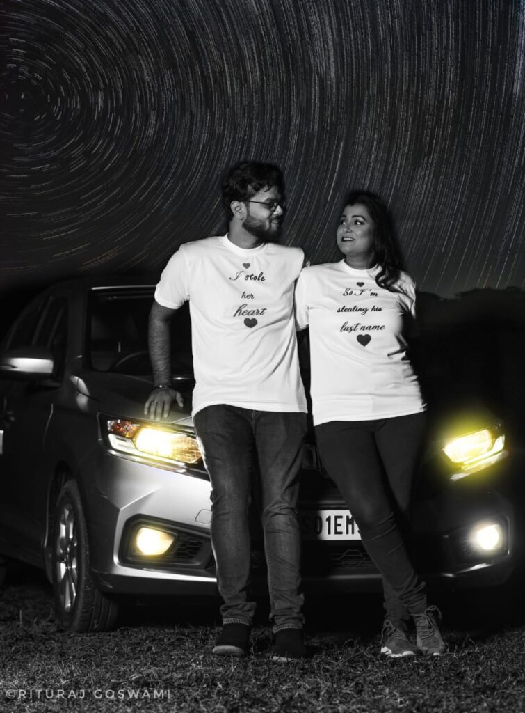 A boy and a girl wearing matching t-shirts, posing beside a car.