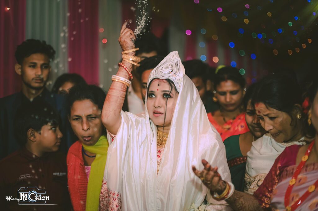Bride performing wedding rituals with a crowded gathering.