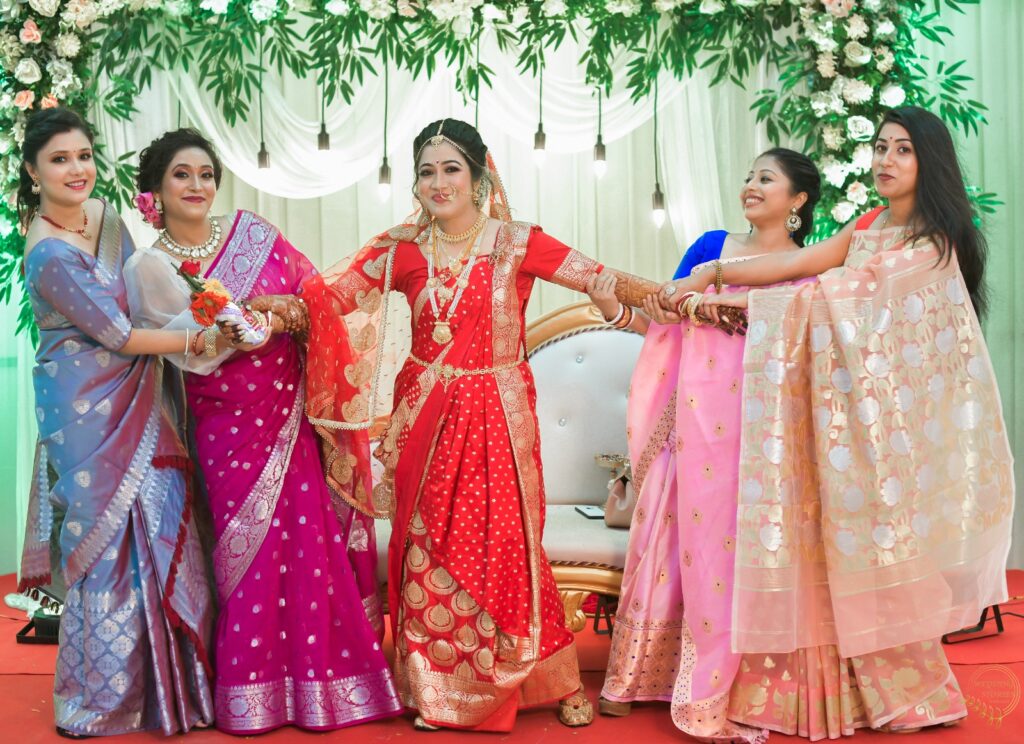 A bride being pulled by her friends from both sides, holding her hands.