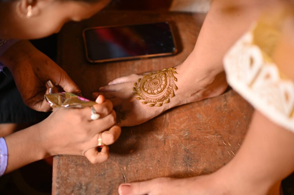 Assamese girl applying henna to another girl's feet.