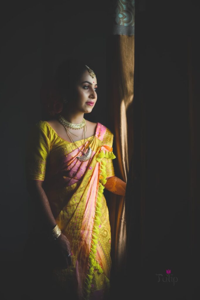 Girl wearing a sari looking outside through the window.
