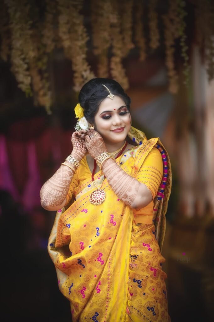 A smiling girl holding her ear ring while striking a pose for a photograph.
