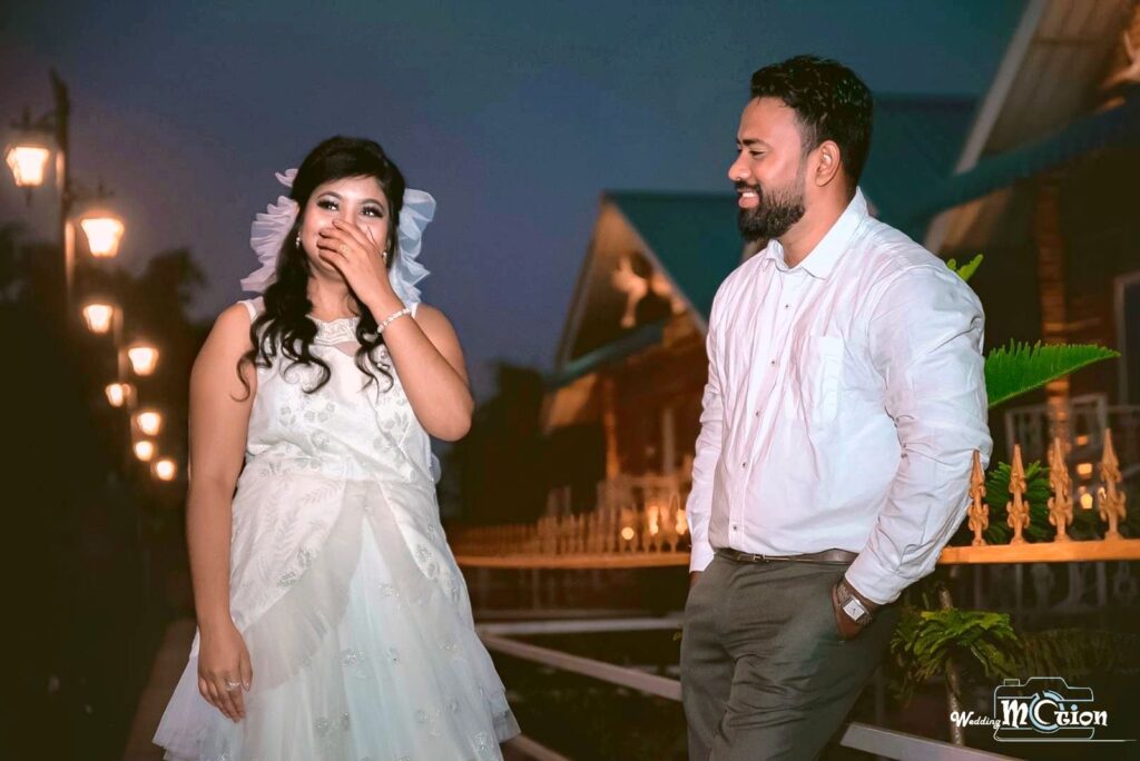 Bride laughing with her hand on her face while the groom gazes at her.
